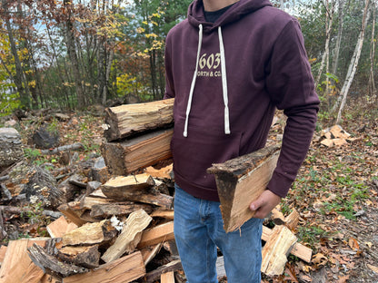 Someone stacking wood wears the 603 North Deer Hoodie. 